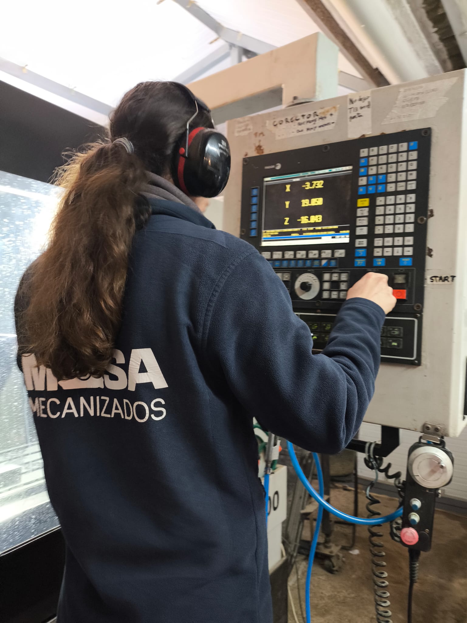 Operario trabajando en el panel de control CNC